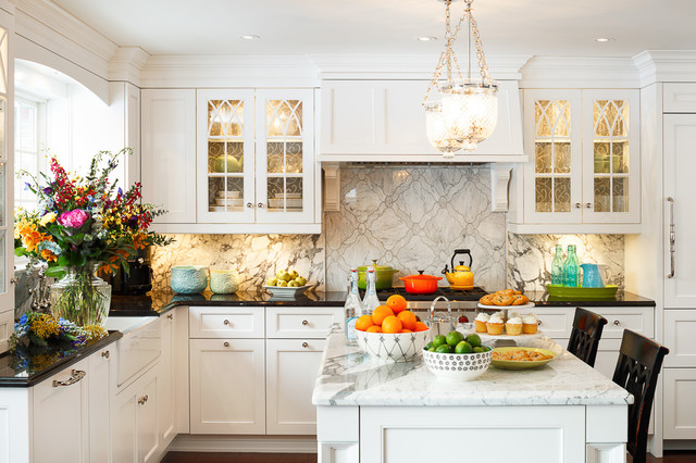 A modern kitchen with glass cabinet doors and mirrored wall panels, enhancing light reflection and the appearance of a larger space.